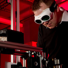 Researcher using laser equipment wearing dark safety goggles