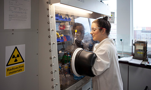 Researcher in white lab coat conducting experiment in machine